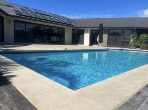 a swimming pool inset into a deck with concrete strip around edge that has been bush hammered to make non-slip texture