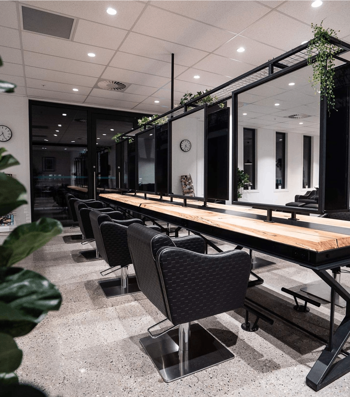 polished concrete floor with table in centre of the room and black padded leather chairs around it