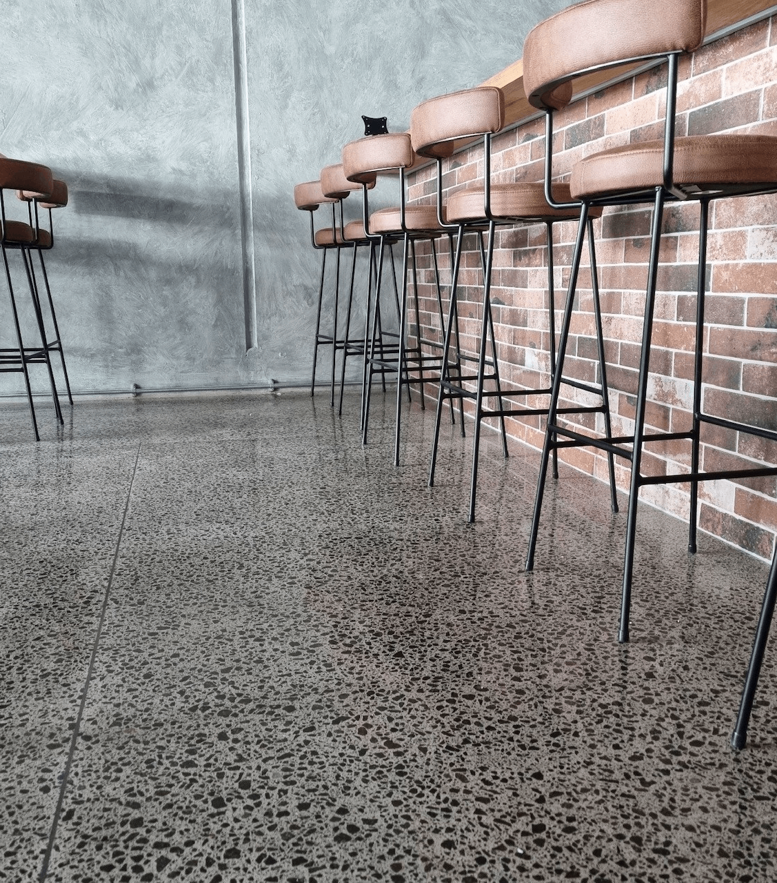 close up of a polished concrete floor at saltwater restaurant with barstools to the right and a brick bar upstand