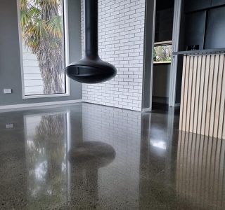NZ Grinders Tauranga Polished concrete floor in kitchen diner area with hanging fireplace