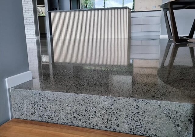 polished concrete step in a house with a kitchen diner in upper area and hardwood floor in lower area